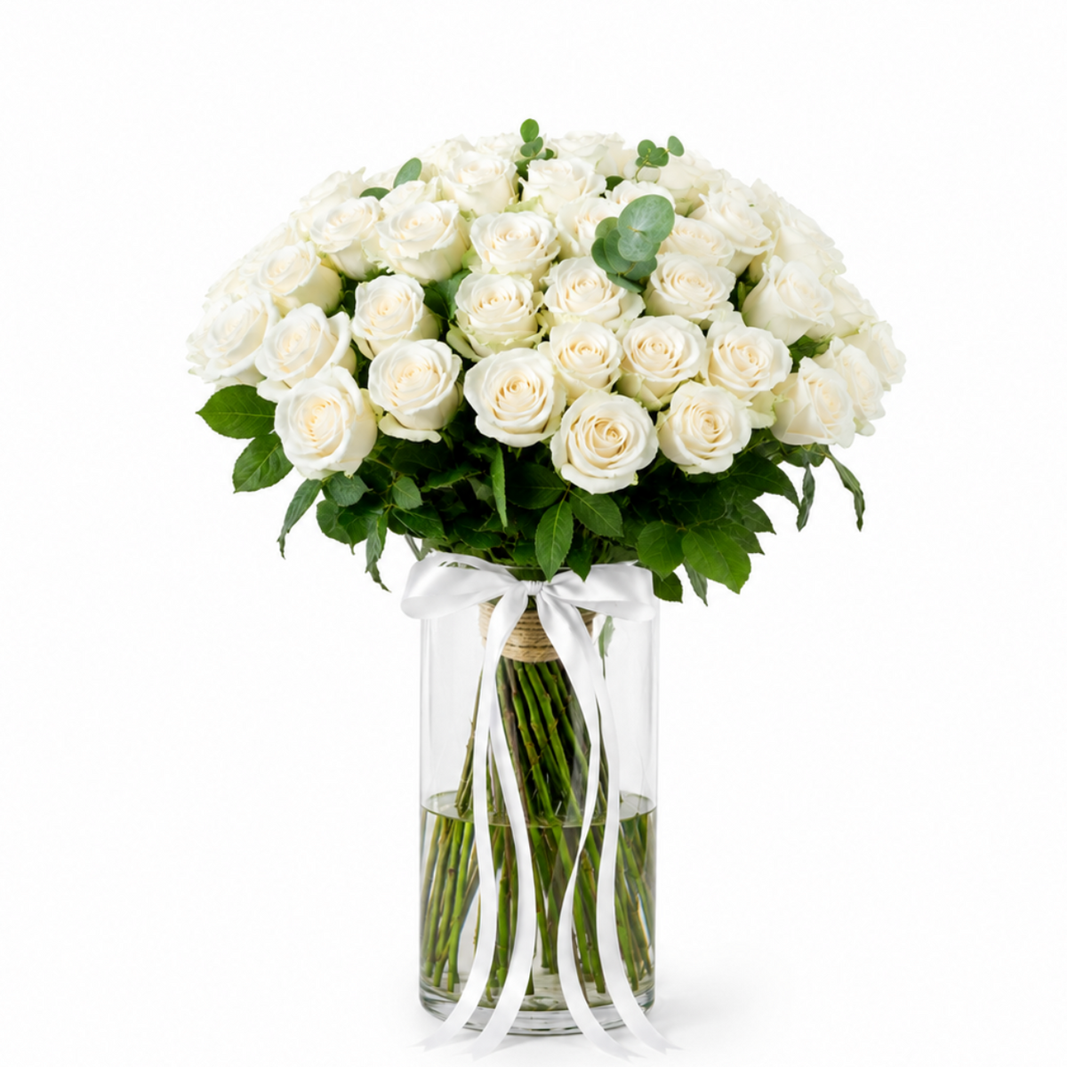 A bouquet of 25 white roses with green eucalyptus stems in a clear glass vase tied with a white ribbon