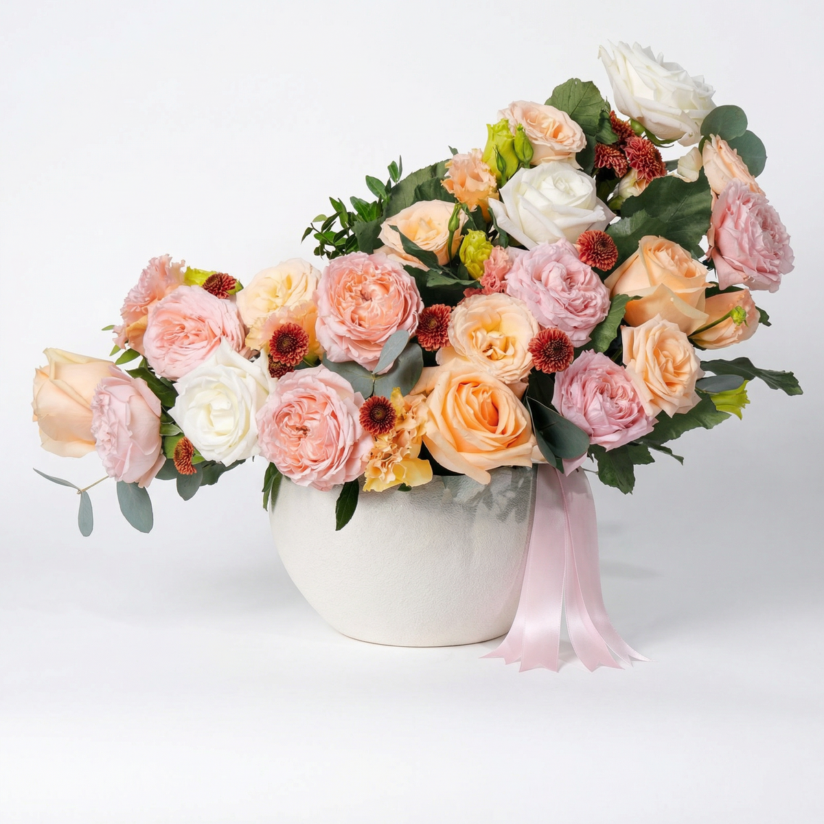Bouquet of flowers in a white vase with a pink ribbon