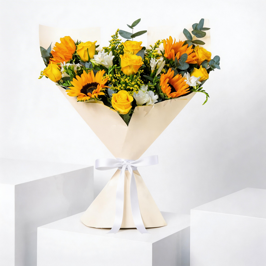 Warm, bright, and effortlessly elegant, this hand-tied bouquet combines yellow roses, white freesia, and glowing sunflowers. A beautifully balanced arrangement that brings joy, light, and a touch of golden charm to any occasion.