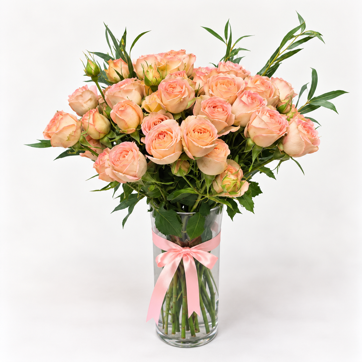 10 peach baby rose stems arranged with fresh greenery in an elegant vase.