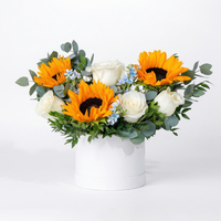 Floral arrangement with sunflowers and white roses in a white box on a light background