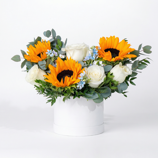 Floral arrangement with sunflowers and white roses in a white box on a light background